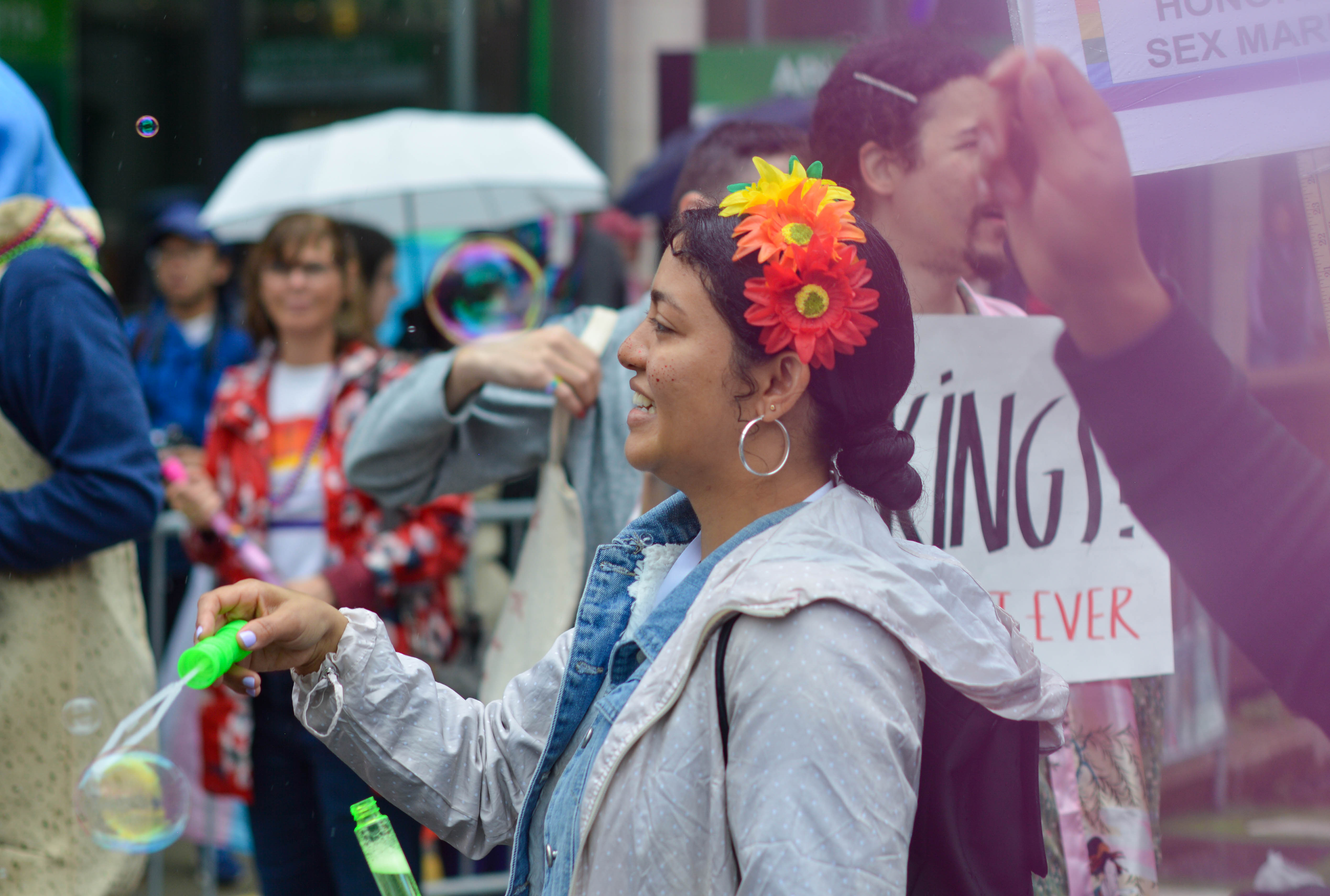 a woman in a pride parade blows a bubble