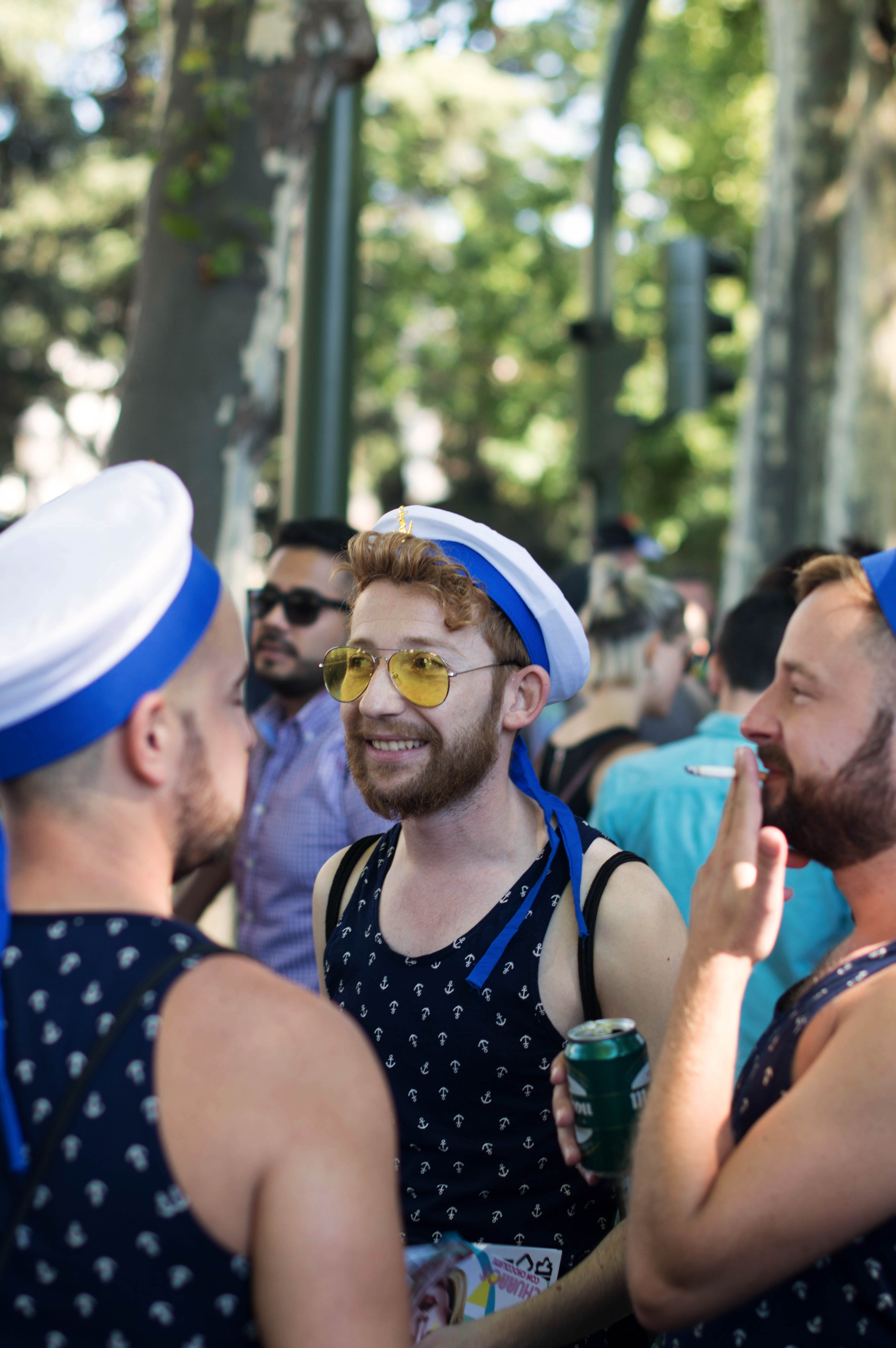 three people at a pride parade dressed as sailors