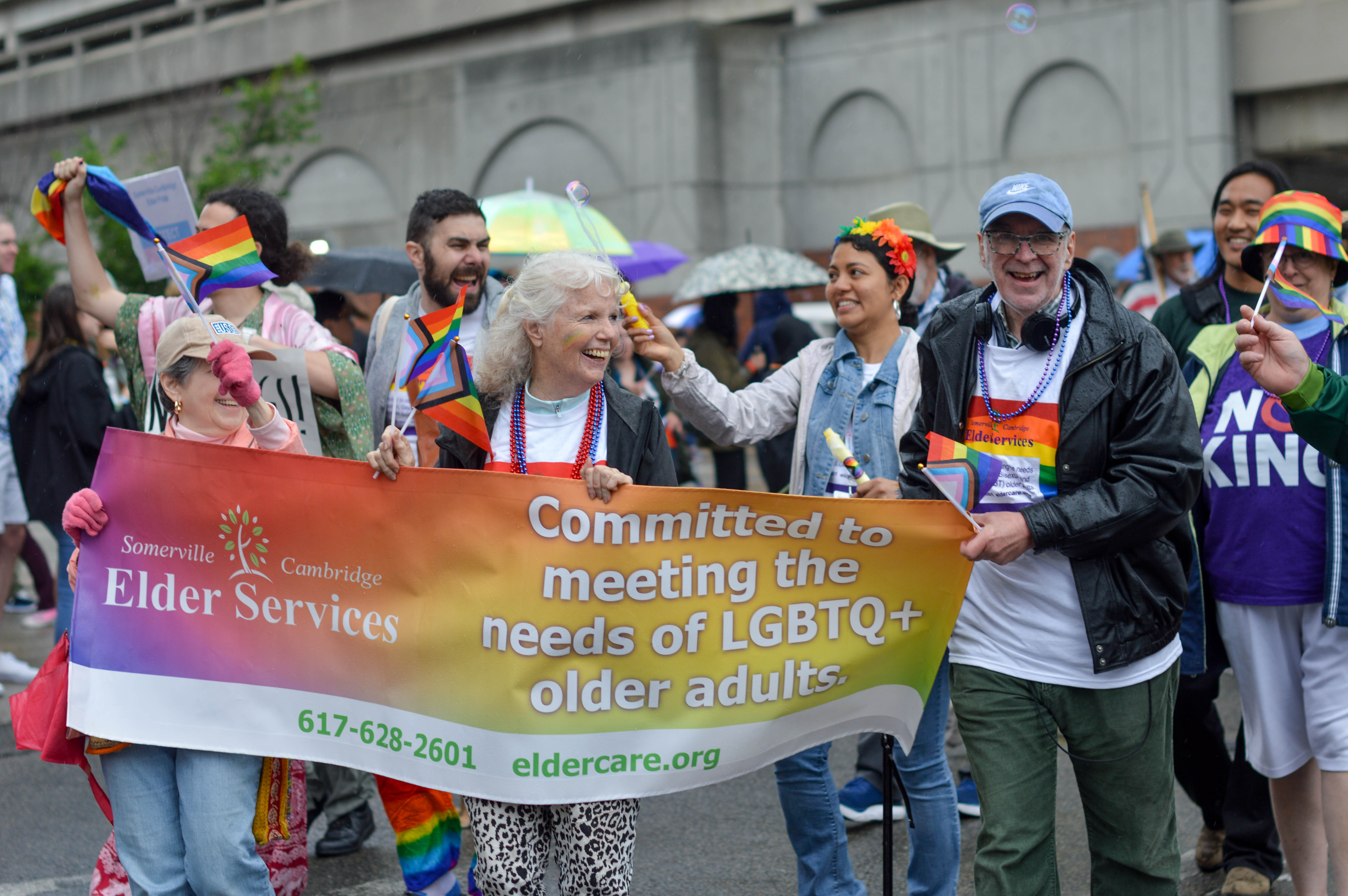 a group of volunteers holding a banner in a pride parade
