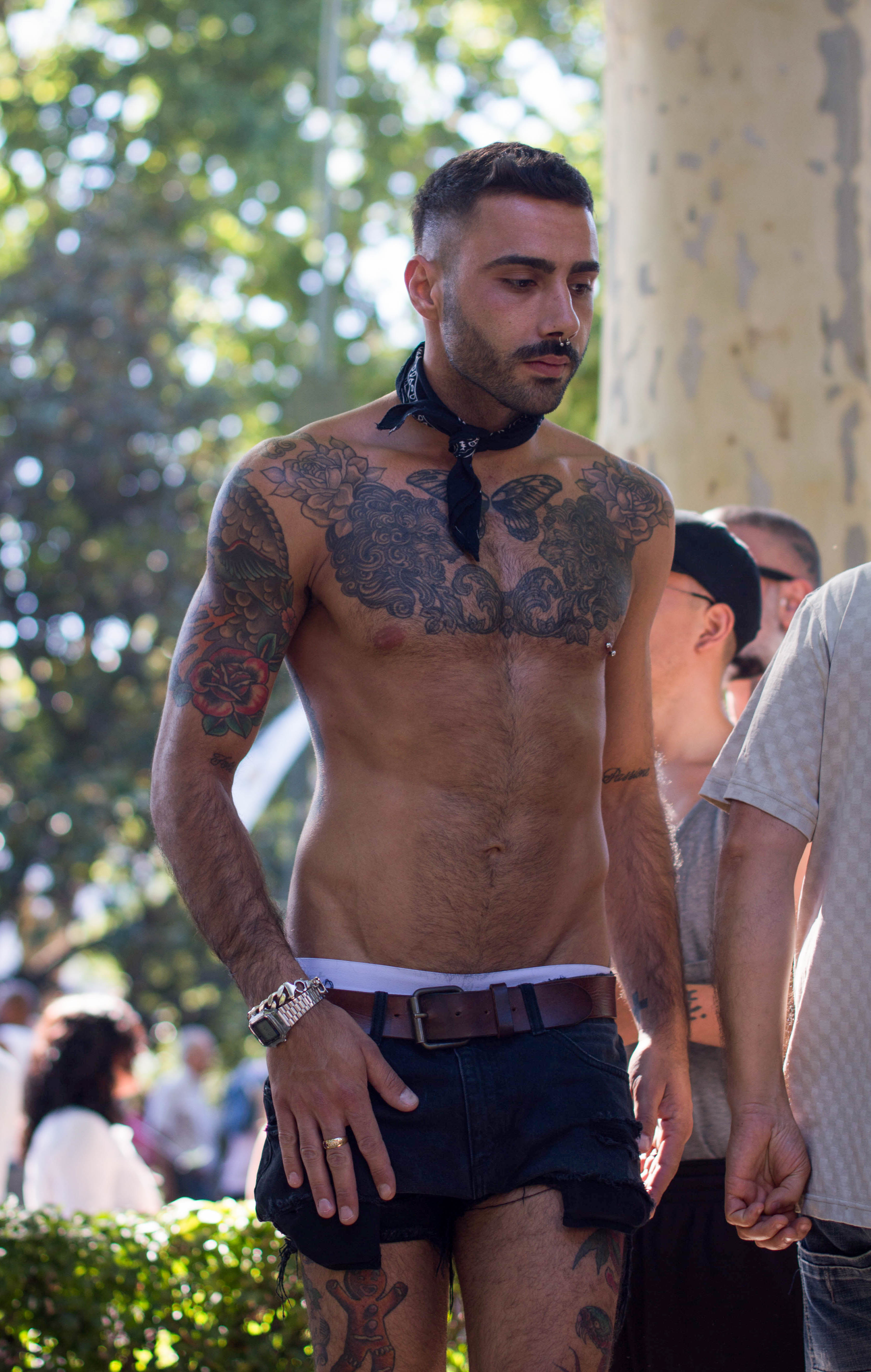 a person with a bare chest and tattoos at a pride parade