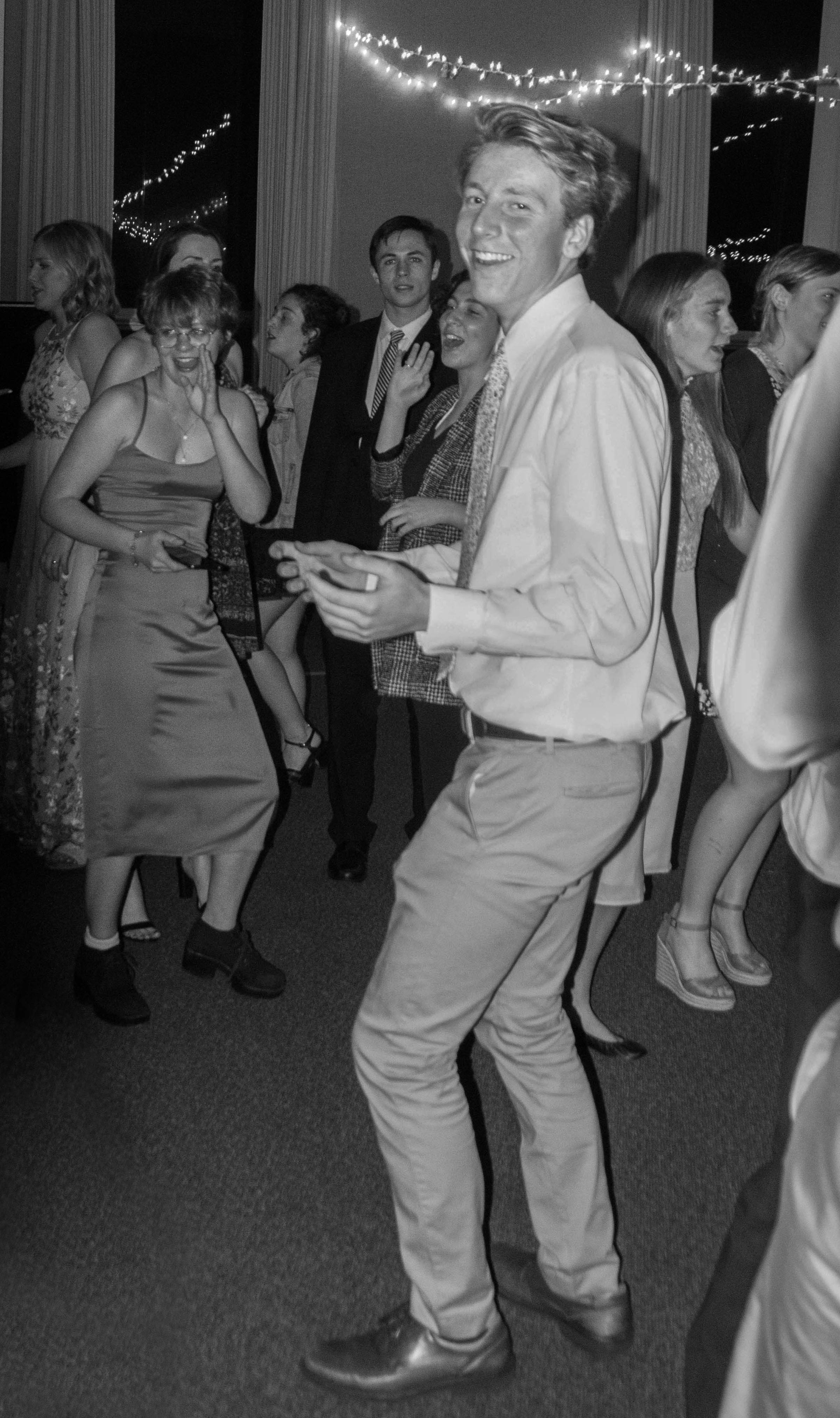 a black and white photo of a young man dancing at a wedding