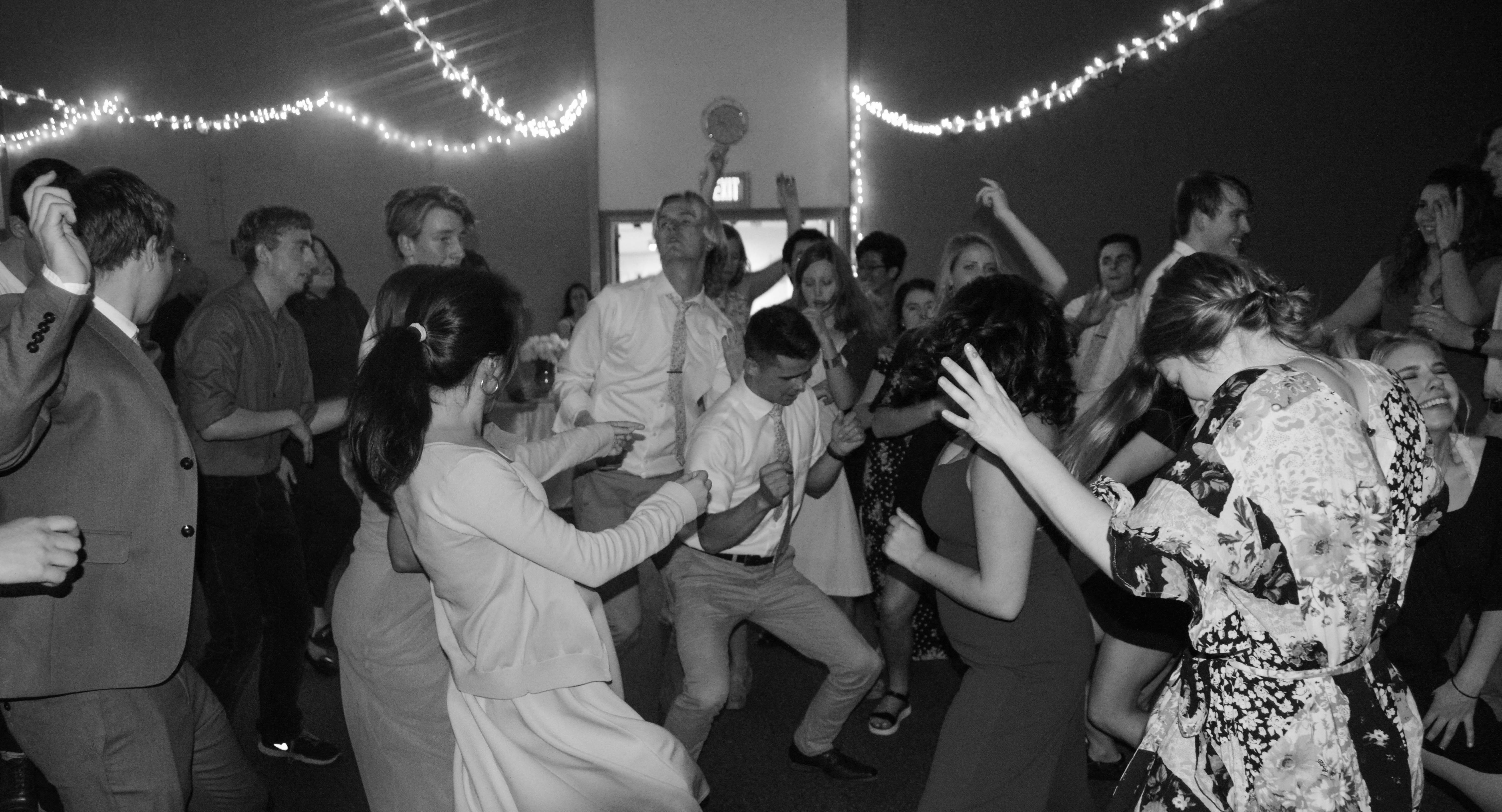 a black and white photo of people dancing at a wedding reception