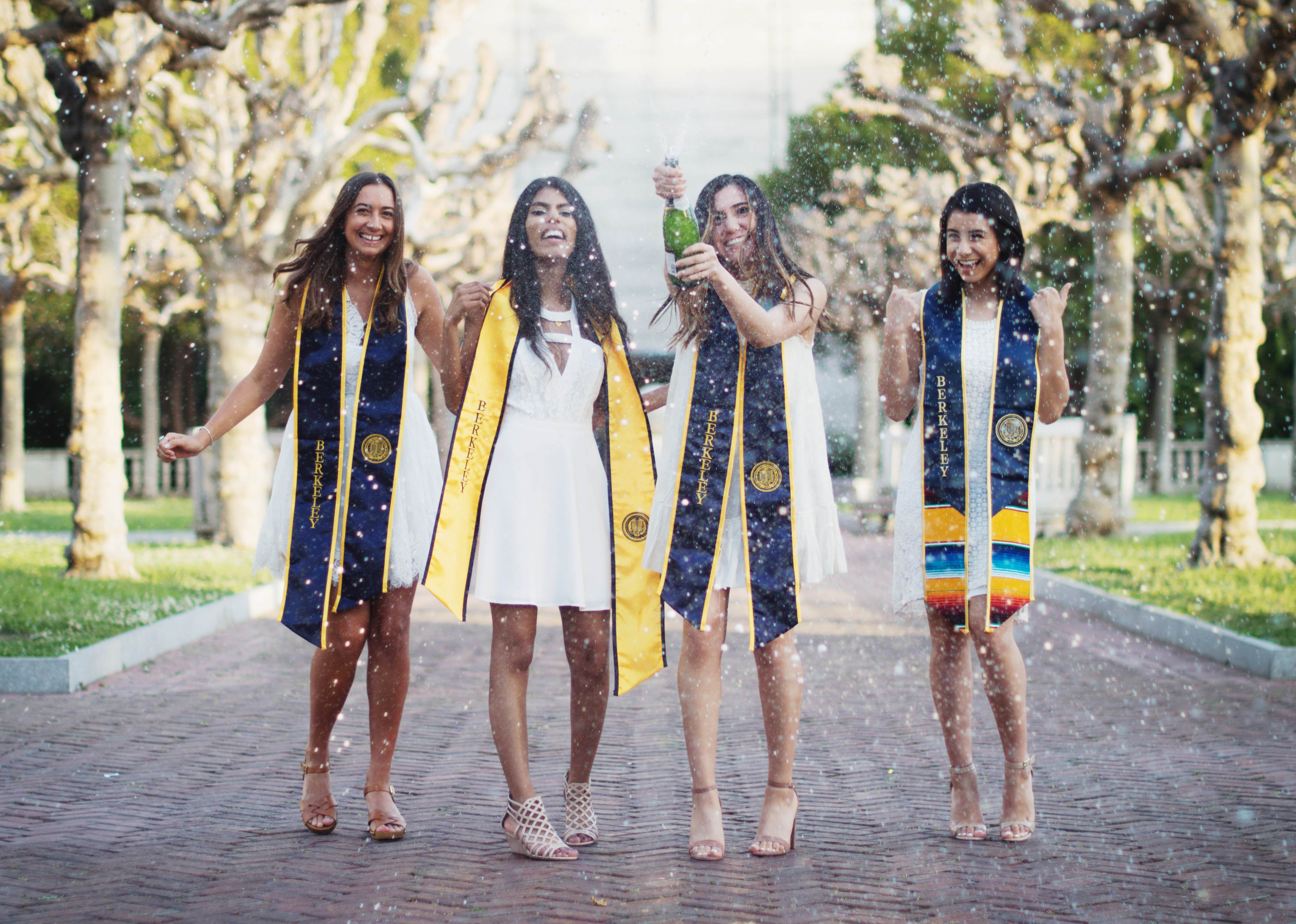 four graduates popping a bottle of champagne