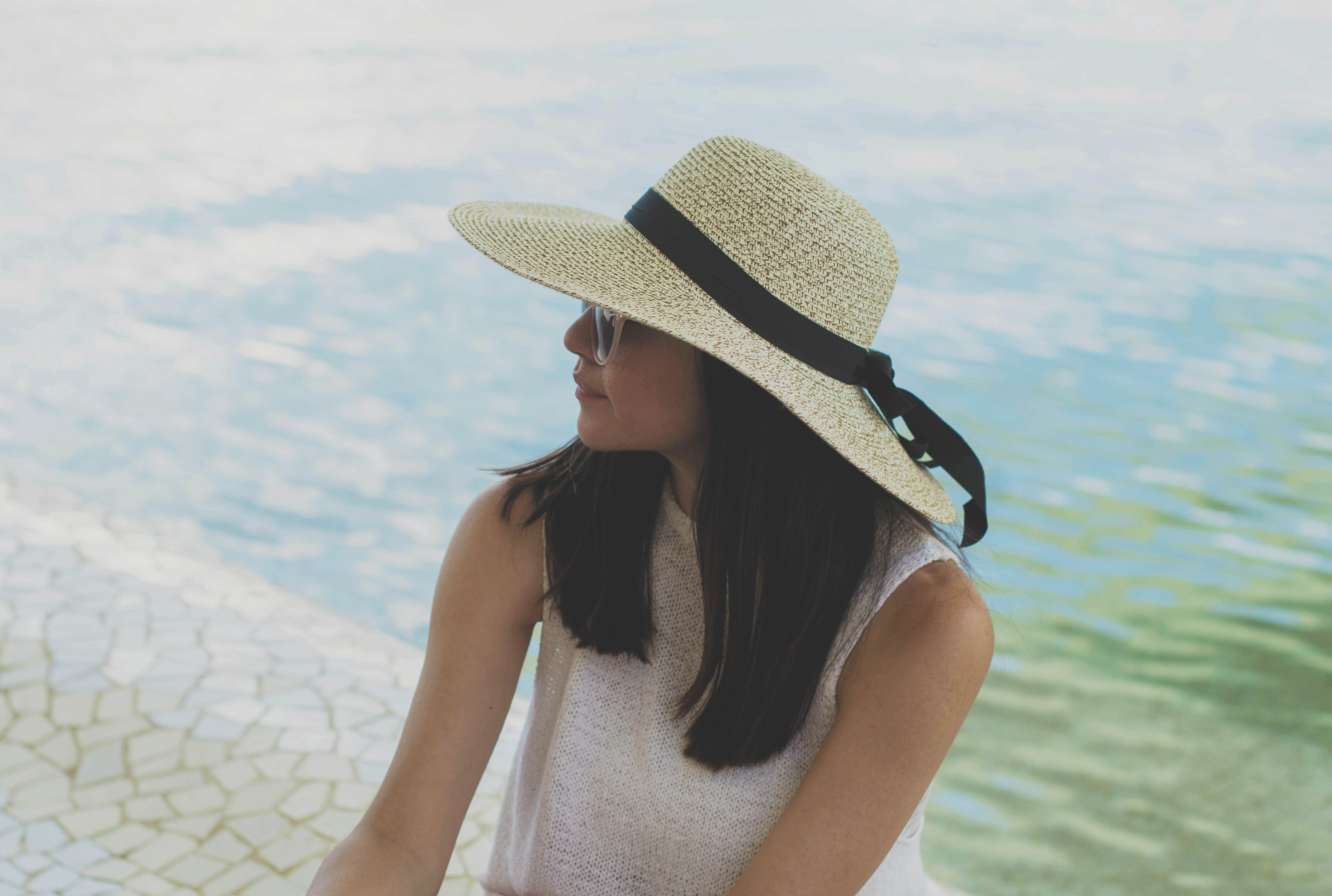 a woman in a hat relaxes near a pool