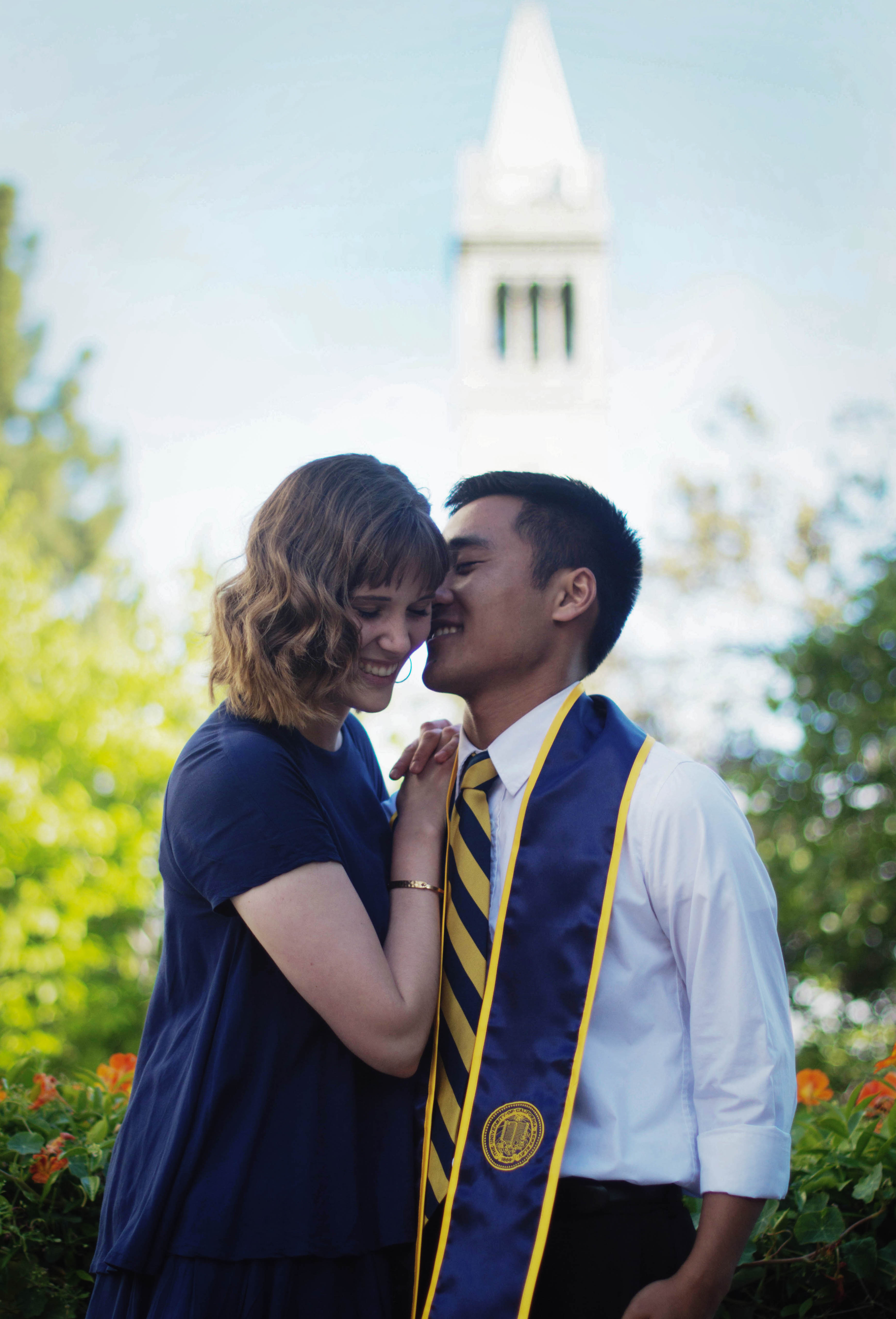 a young couple poses lovingly in front of a tower