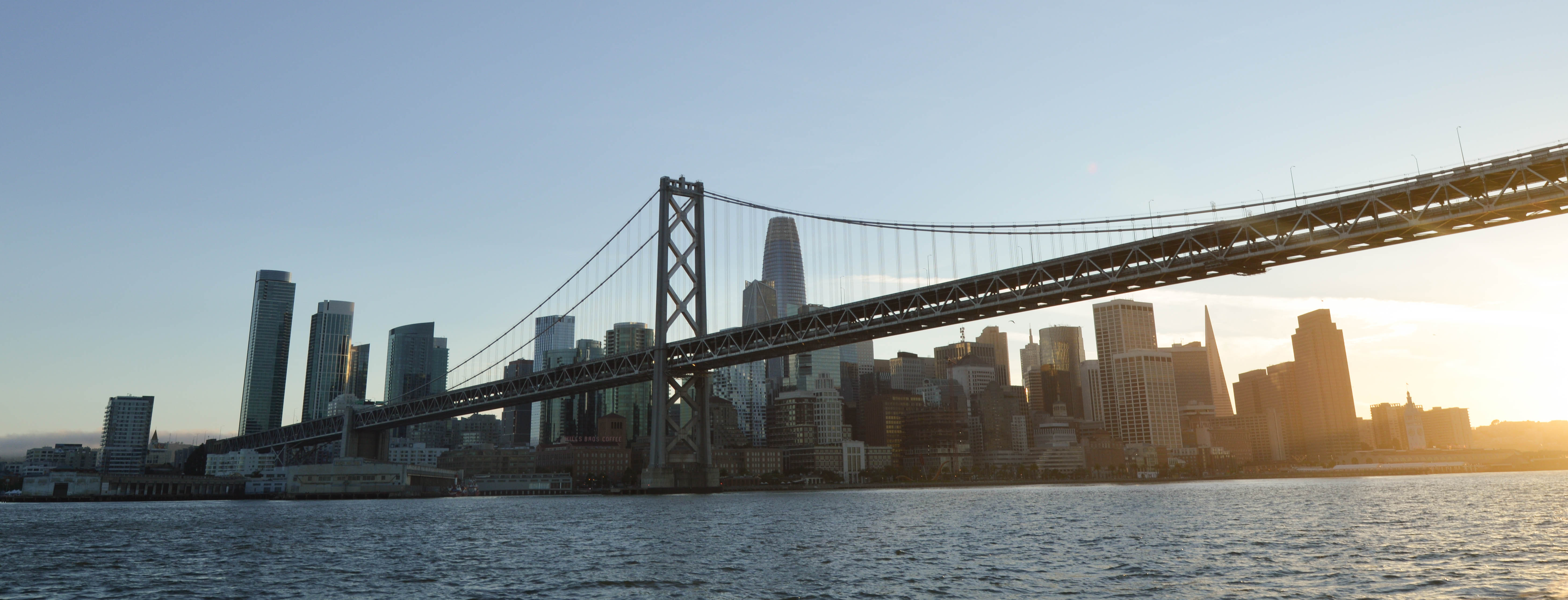 the san francisco skyline and bay bridge at sunset