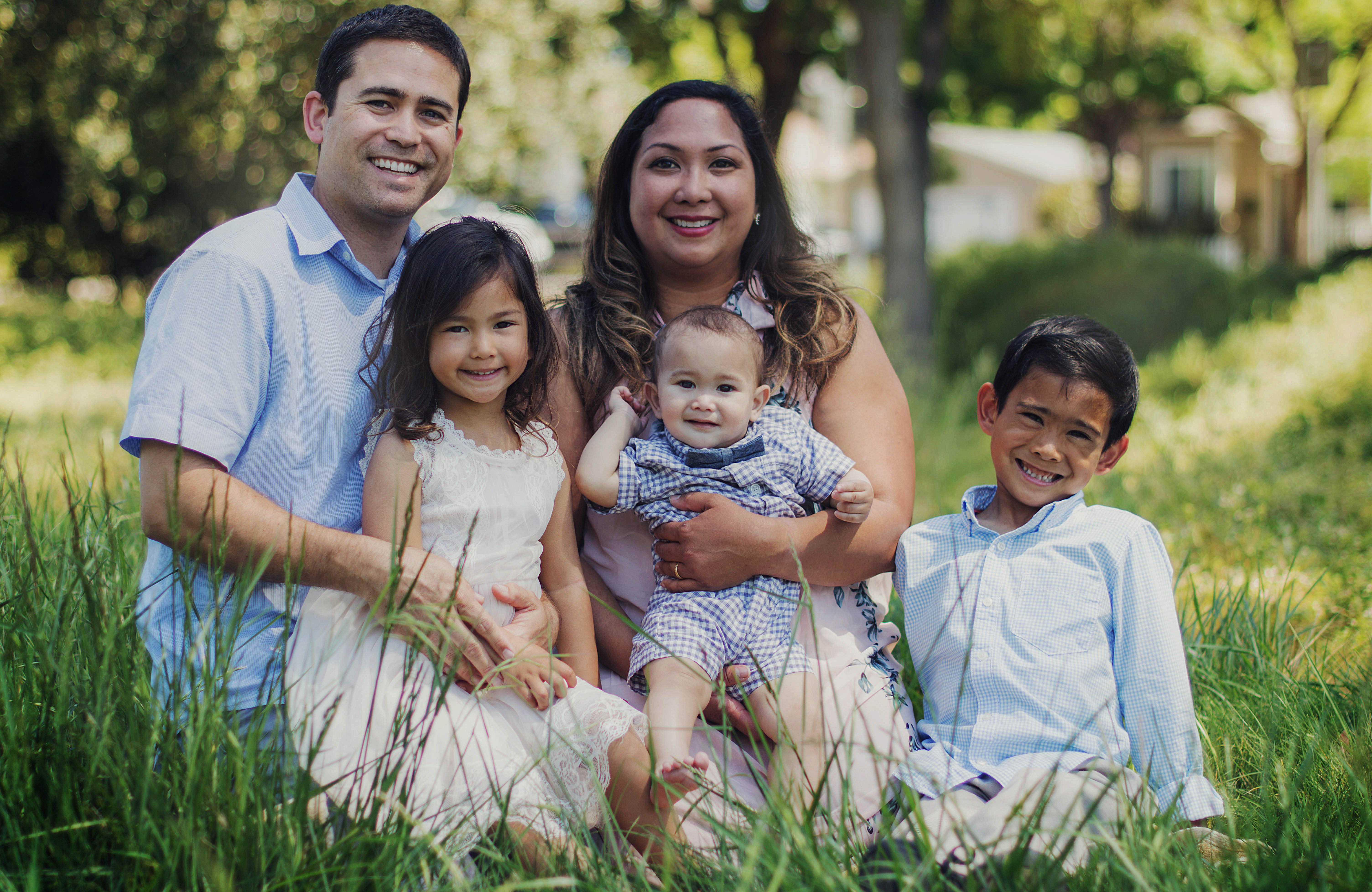 a family sits in the grass for a formal portrait