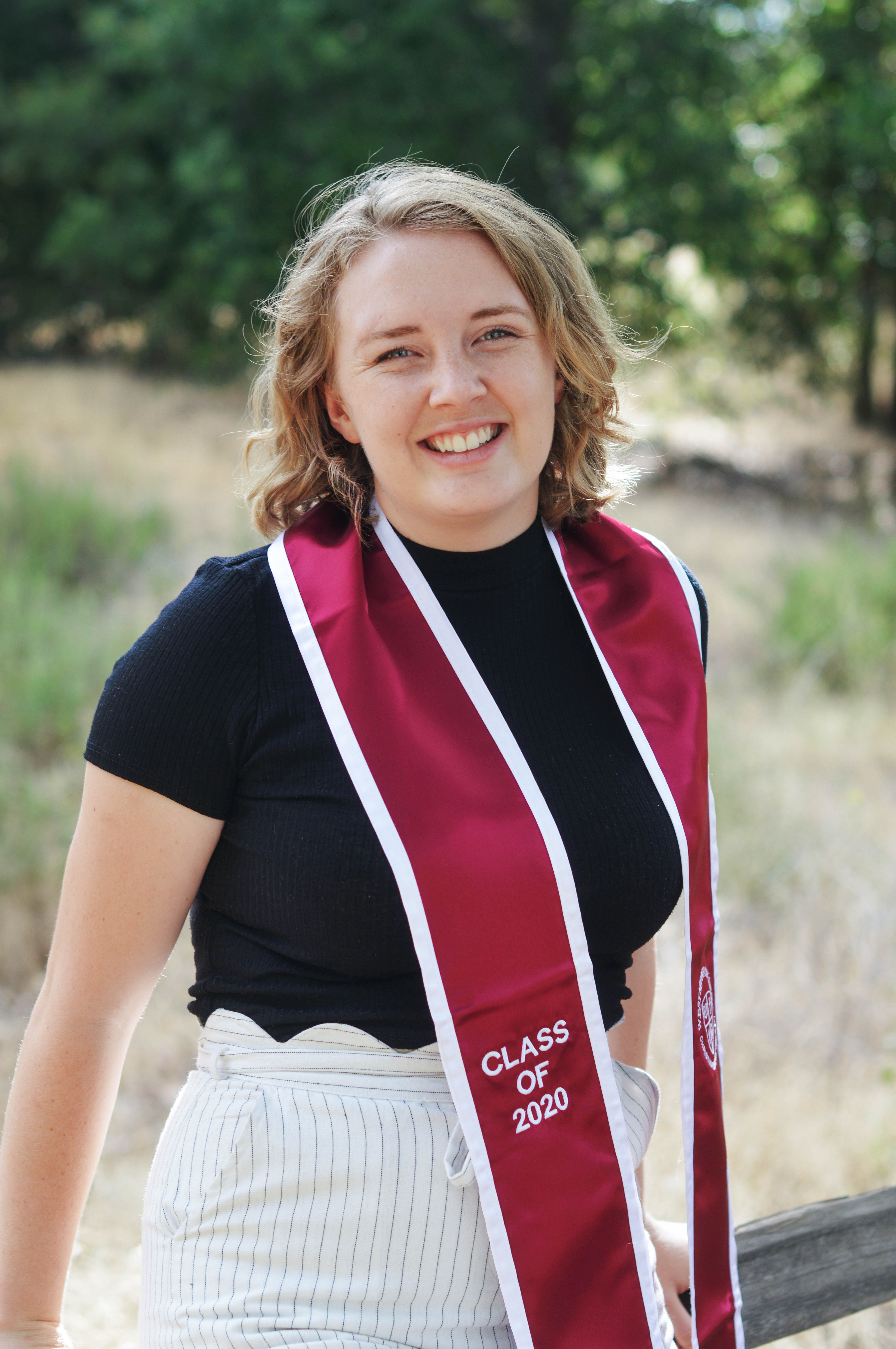 a young woman smiling and wearing a graduation stole