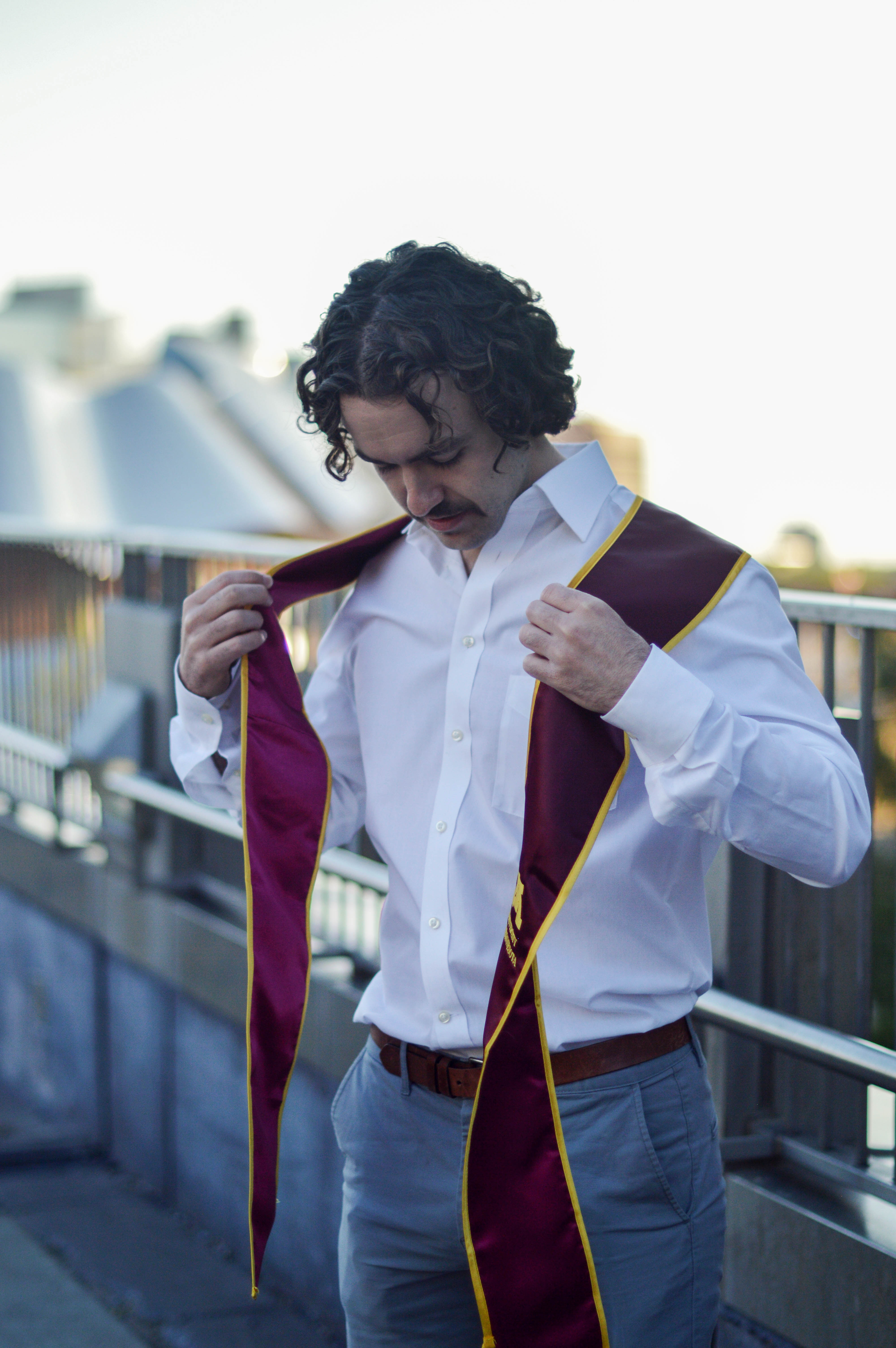 a young man arranges his graduation stole